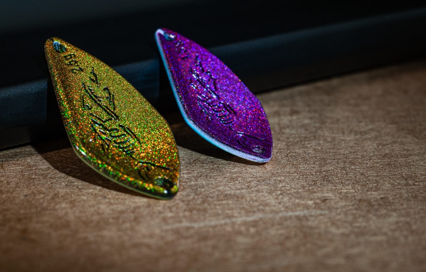 Spoons angeln mit PROBAITS Floki – Gold & Lila Spoon im Detail Zwei PROBAITS Floki Spoons in Gold und Lila mit glitzernder Rückseite, angelehnt an einer Wand – perfektes Beispiel fürs Spoons angeln.